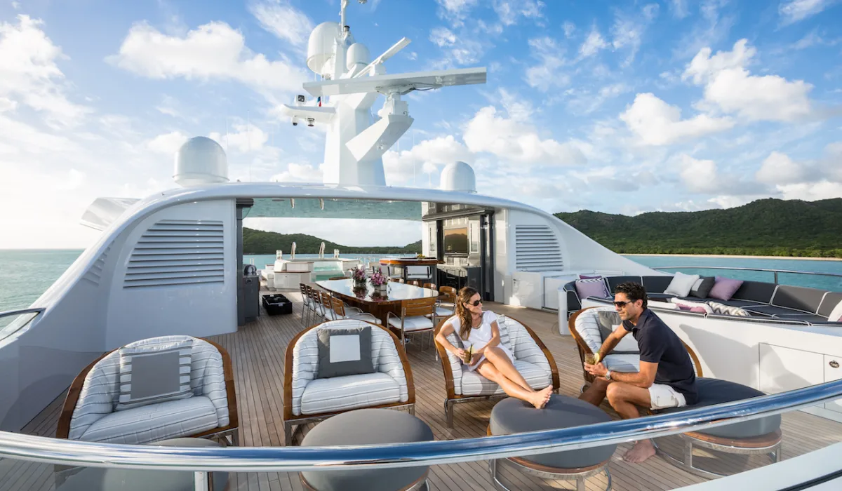 Guests relaxing on deck with coastal mountains behind